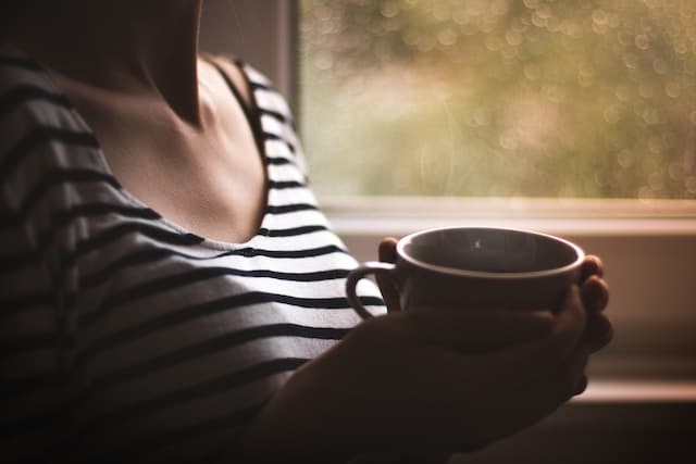 Woman in black and white striped top holding white ceramic mug