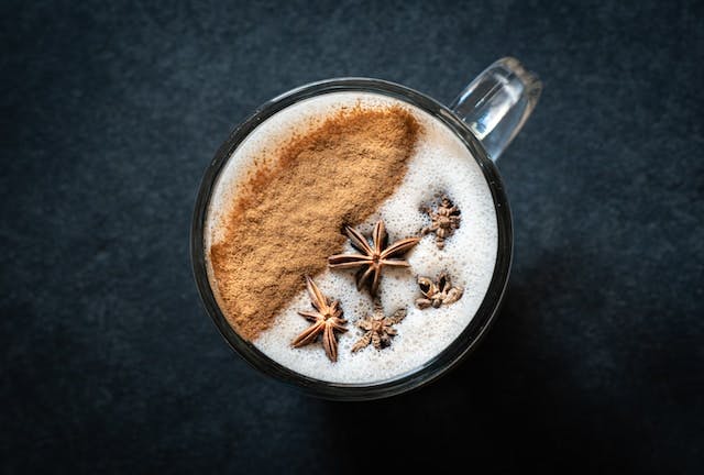 A cup of chai with cinnamon and star anise on top