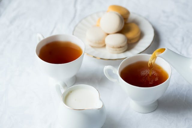 Two cups of tea beside the macaroons on plate